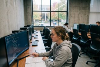 Étudiante en formation développeur IA travaillant sur du code Python dans une salle informatique universitaire