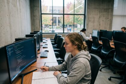 Étudiante en formation développeur IA travaillant sur du code Python dans une salle informatique universitaire